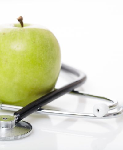 Apple and stethoscope on white background